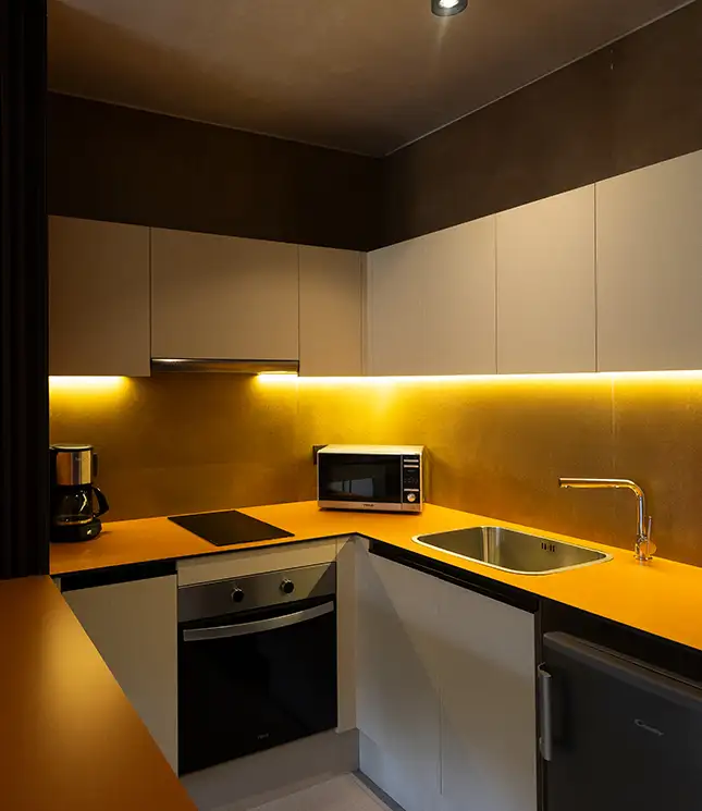 Modern kitchen with yellow lighting and sleek appliances.
