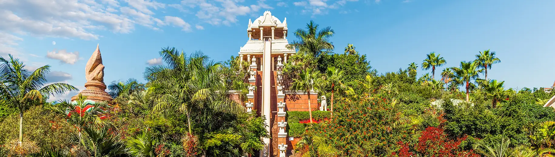 Tropical temple surrounded by lush greenery under a blue sky.