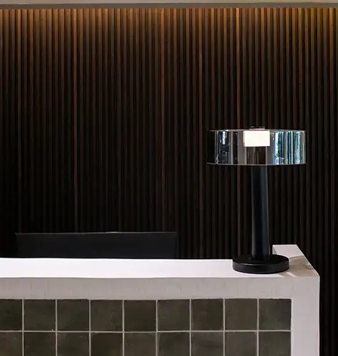 Lamp on a white table against a dark textured wall background.