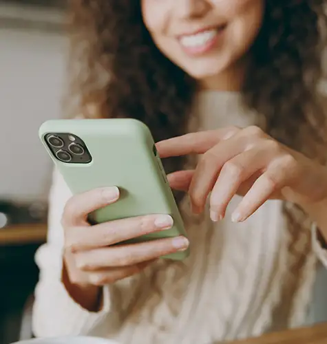 Smiling woman using a smartphone with a green case.