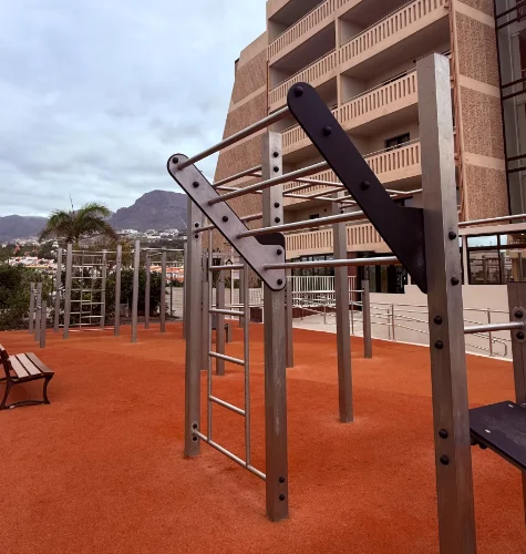 Playground exercise structure with metal bars and ropes beside an apartment building
