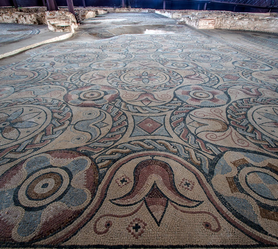 Mosaico antiguo con patrones geom&eacute;tricos en tonos tierra y azul.