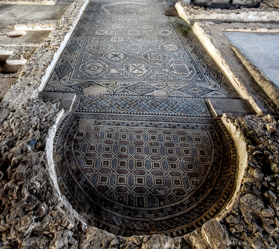 Mosaico antiguo con patrones geom&eacute;tricos en un sitio arqueol&oacute;gico.