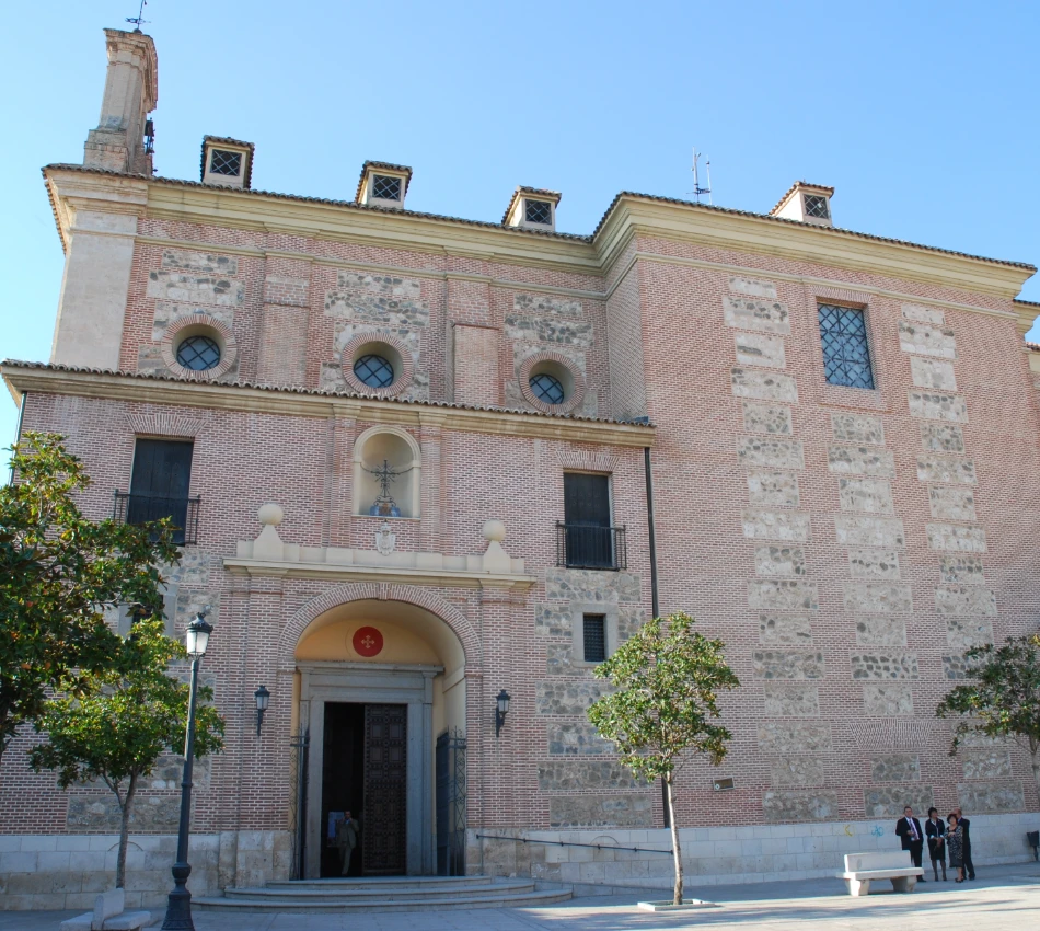 Edificio hist&oacute;rico de ladrillo con puerta arqueada y &aacute;rboles al frente.