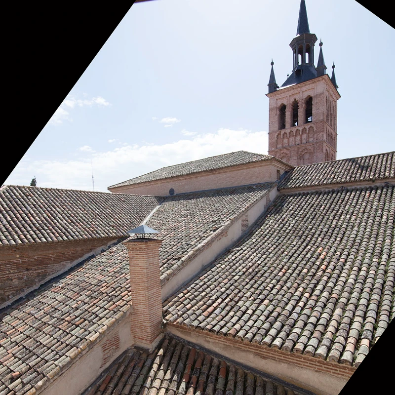 Tejado de tejas y torre de iglesia con cielo despejado.