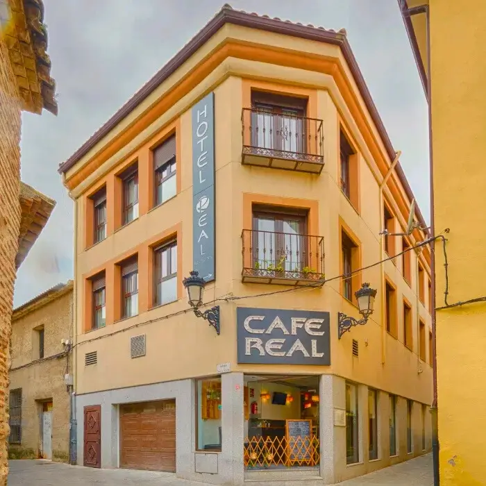 Edificio esquinero color crema con letreros de "Hotel Real" y "Caf&eacute; Real".