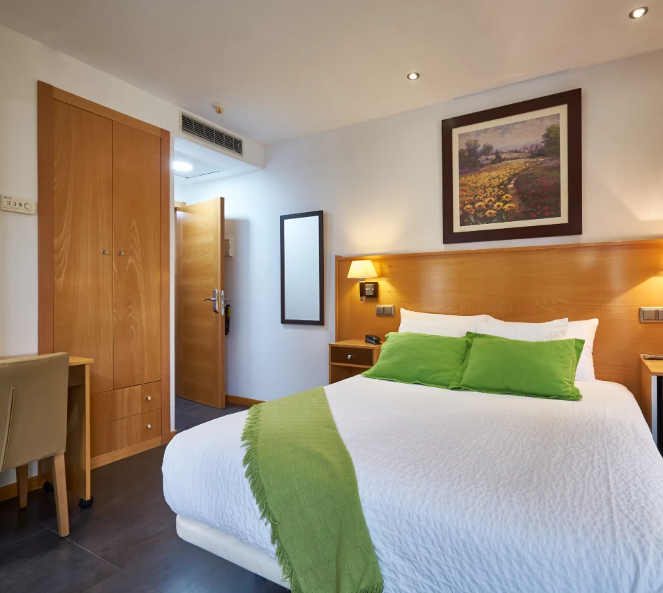Habitaci&oacute;n de hotel moderna con cama, armario y decoraci&oacute;n sencilla.