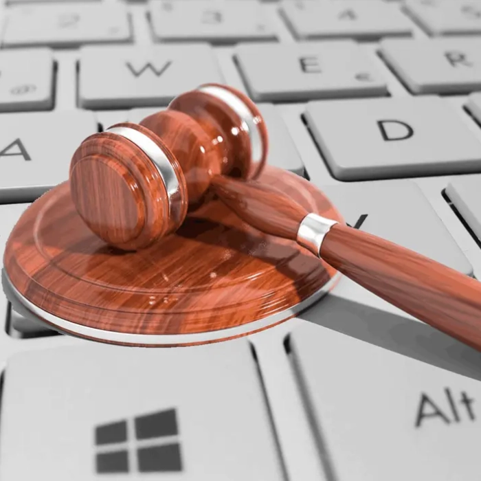 Mazo de juez sobre teclado gris de computador, simboliza leyes digitales.