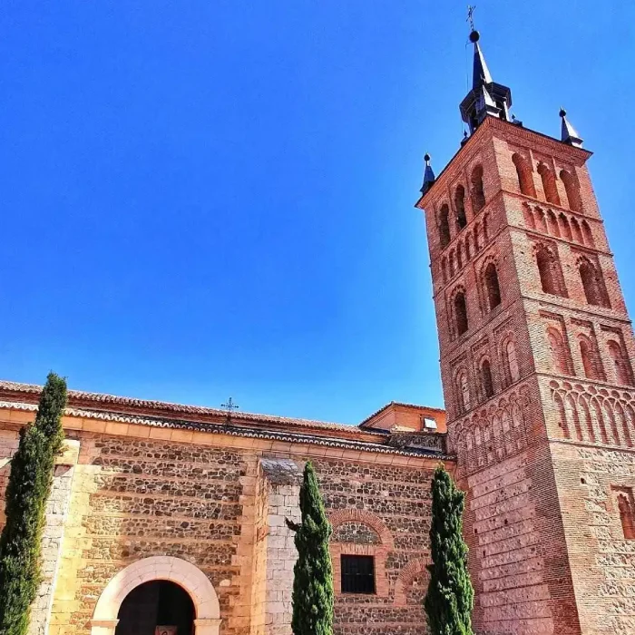 Iglesia de ladrillo con torre alta y cielo azul.