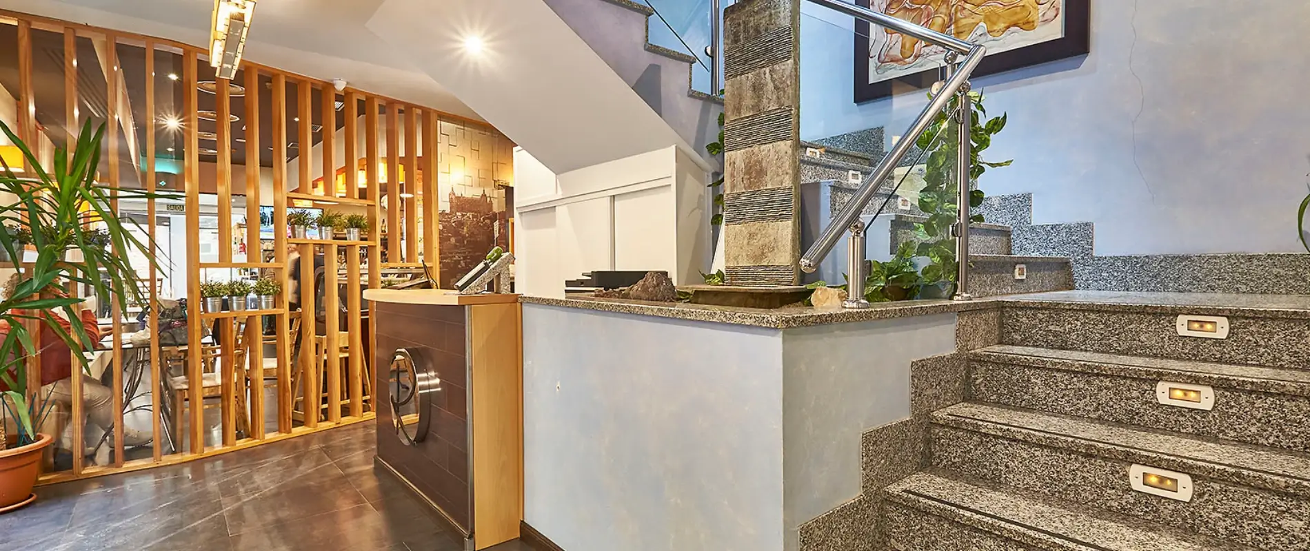 Recepci&oacute;n moderna con escalera y decoraci&oacute;n de plantas.