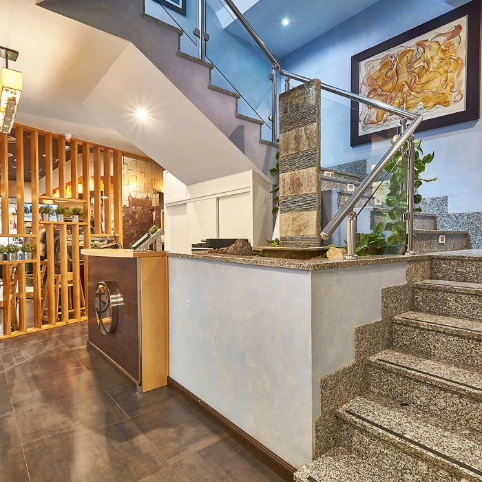 Escaleras modernas con barandilla de vidrio y recepci&oacute;n en un espacio iluminado.
