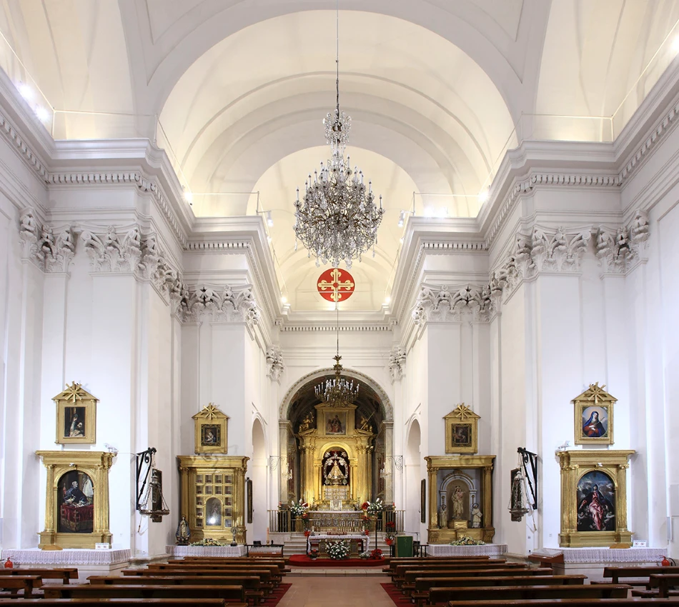 Interior de una iglesia barroca con altar ornamentado y candelabro colgante.