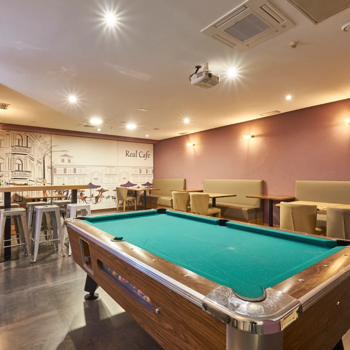 Mesa de billar en un caf&eacute; moderno con asientos y decoraci&oacute;n urbana.