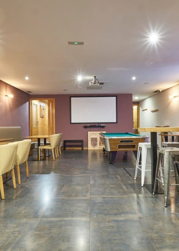 Sala de juegos moderna con billar, sillas y proyector.