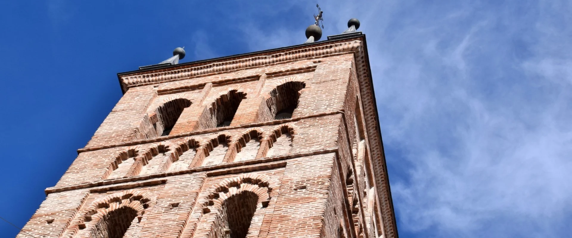 Torre de ladrillo marr&oacute;n con cielo azul de fondo.