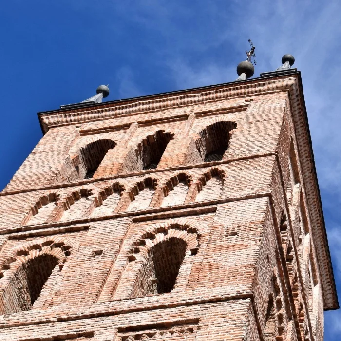 Torre de ladrillo con arcos bajo un cielo azul.