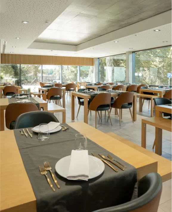 Restaurante moderno com mesas postas e grandes janelas de vidro.