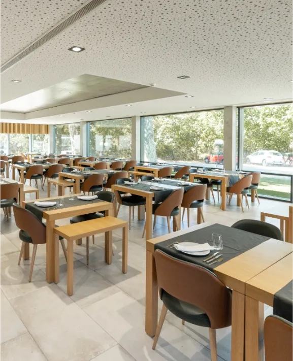 Restaurante com mesas de madeira e cadeiras em ambiente iluminado.