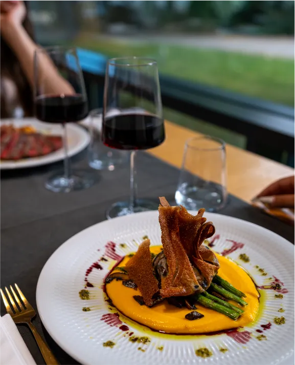 Prato gourmet com vinho tinto sobre a mesa de um restaurante.