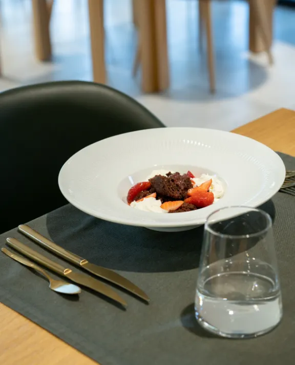 Prato com sobremesa de frutas e creme em mesa de restaurante elegante.