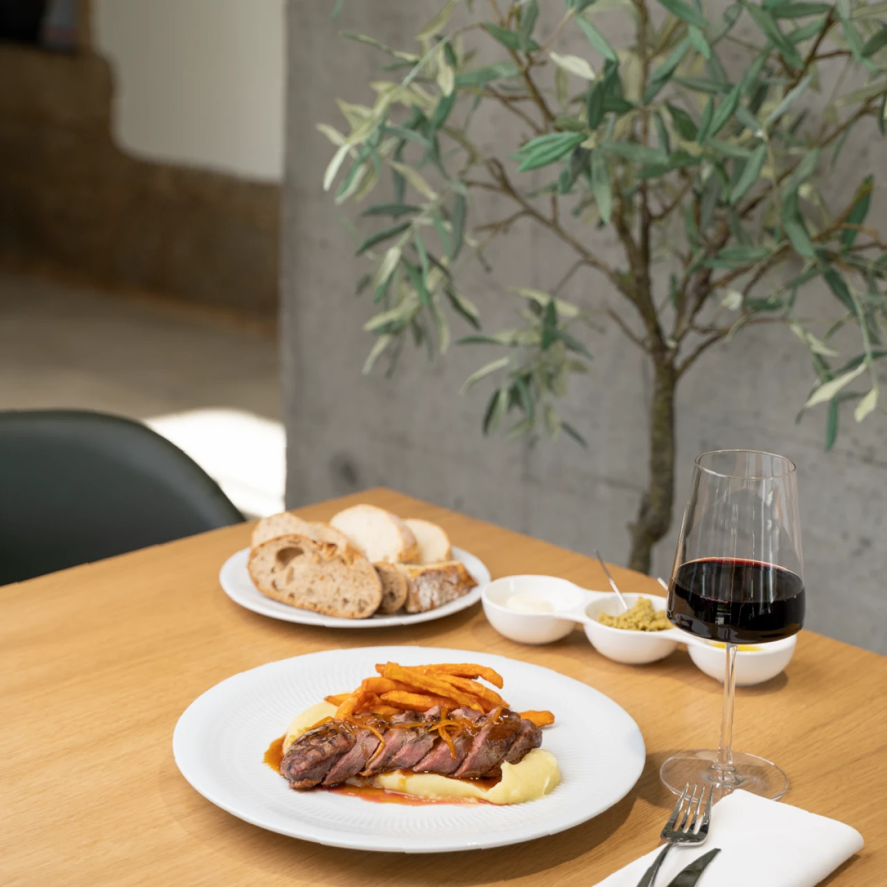 Prato de carne com pur&ecirc;, batatas fritas e vinho tinto sobre a mesa.