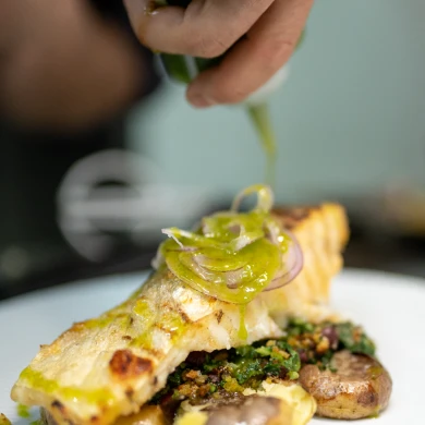 Prato de peixe grelhado com molho sendo servido.