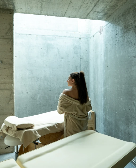 Pessoa de roupão em sala de spa iluminada por luz natural.
