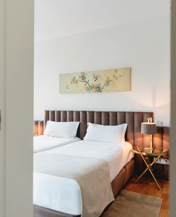 Quarto com duas camas, luminária e quadro na parede.