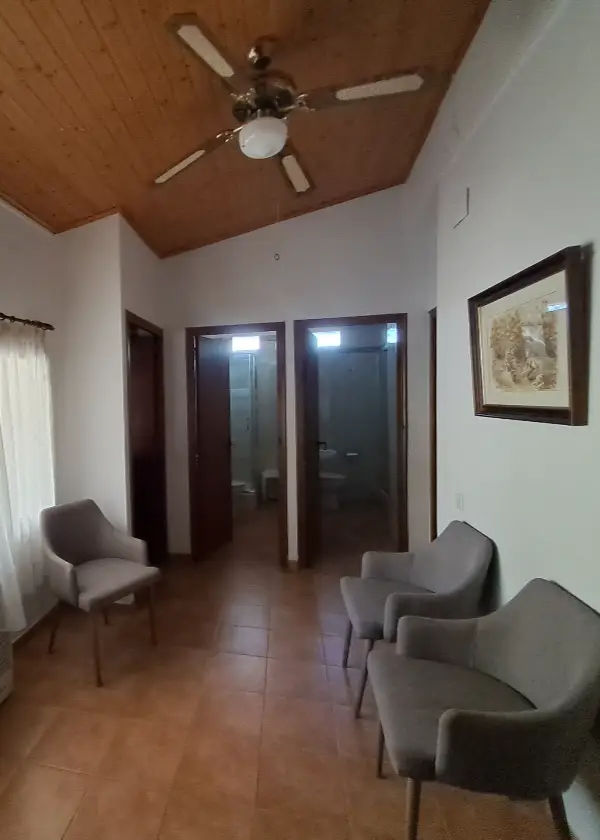 Sala amb cadires grises i portes de fusta, sostre de fusta amb ventilador.