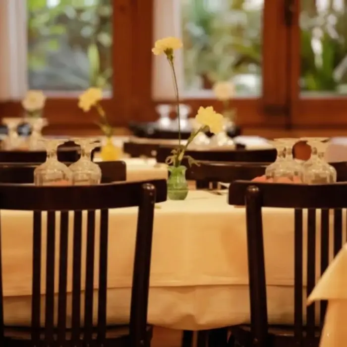 Taules amb flors grogues en un restaurant elegant amb cadires fosques.