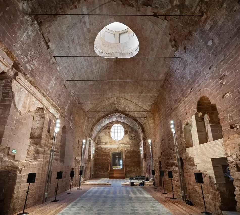 Interior d'una esgl&eacute;sia en ru&iuml;nes amb arcs i sostre alt de pedra.