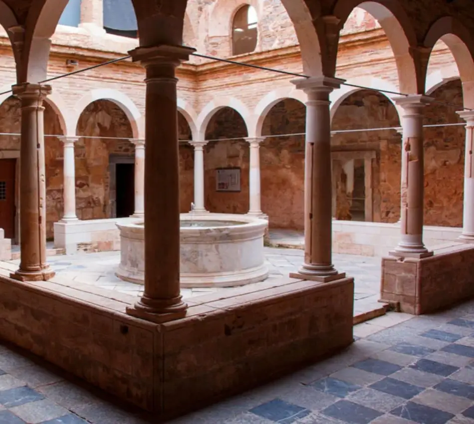 Claustre amb arcs de pedra i un pou central al pati interior.
