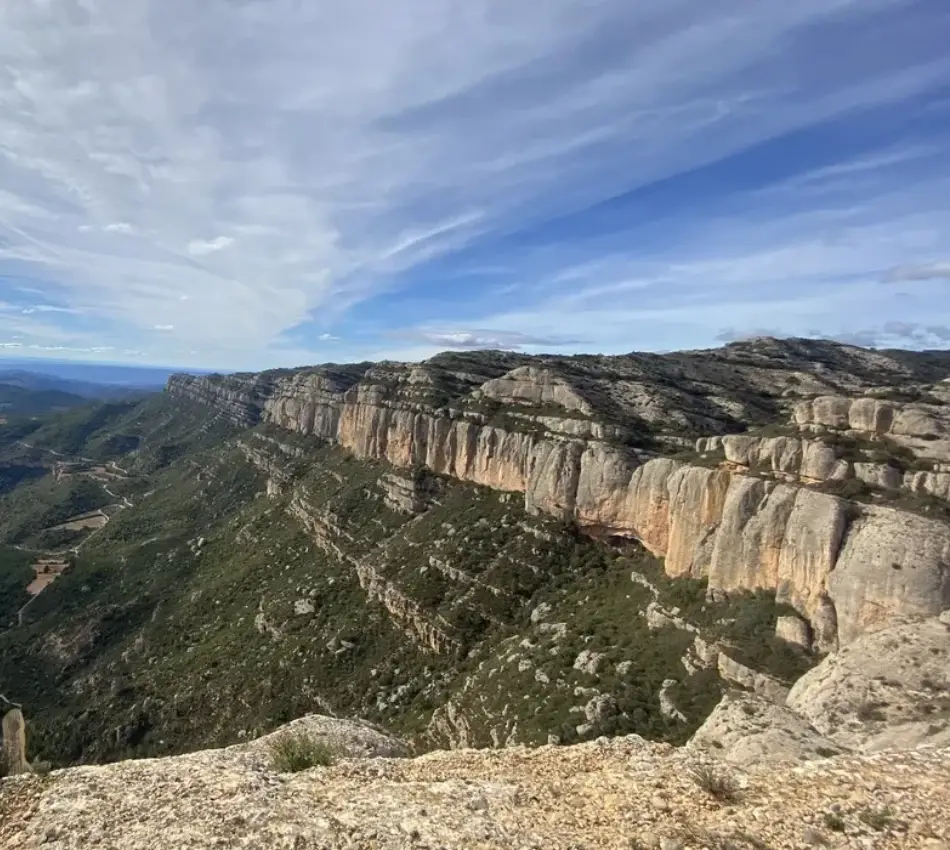Paisatge muntany&oacute;s amb cingles, sota un cel parcialment ennuvolat.