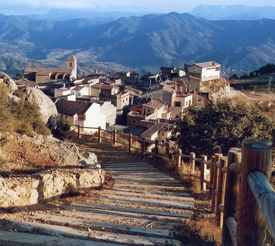 Escales de pedra amb vistes a un poble muntany&oacute;s i esgl&eacute;sia.
