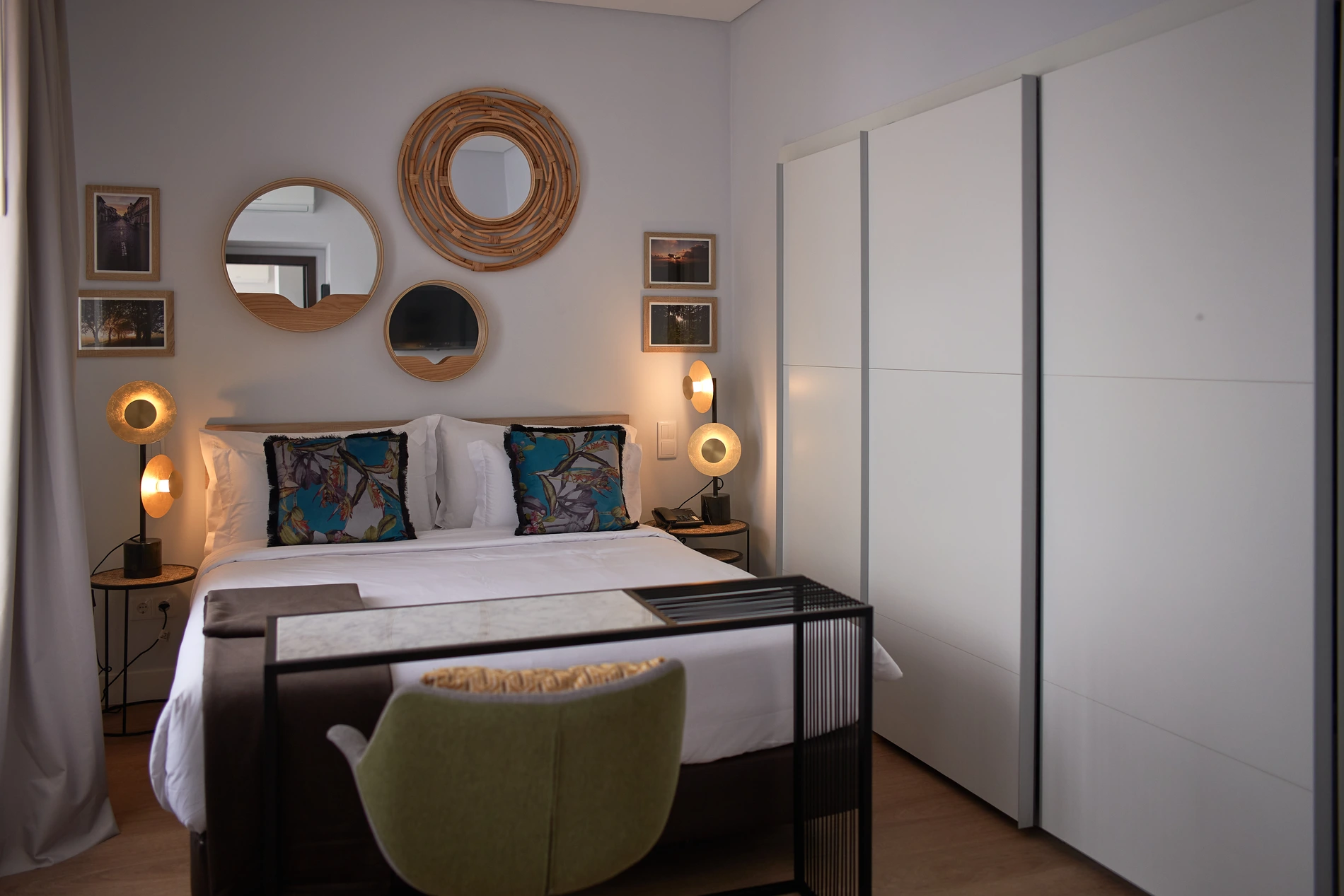 Quarto elegante com cama, espelhos redondos e lumin&aacute;rias modernas.