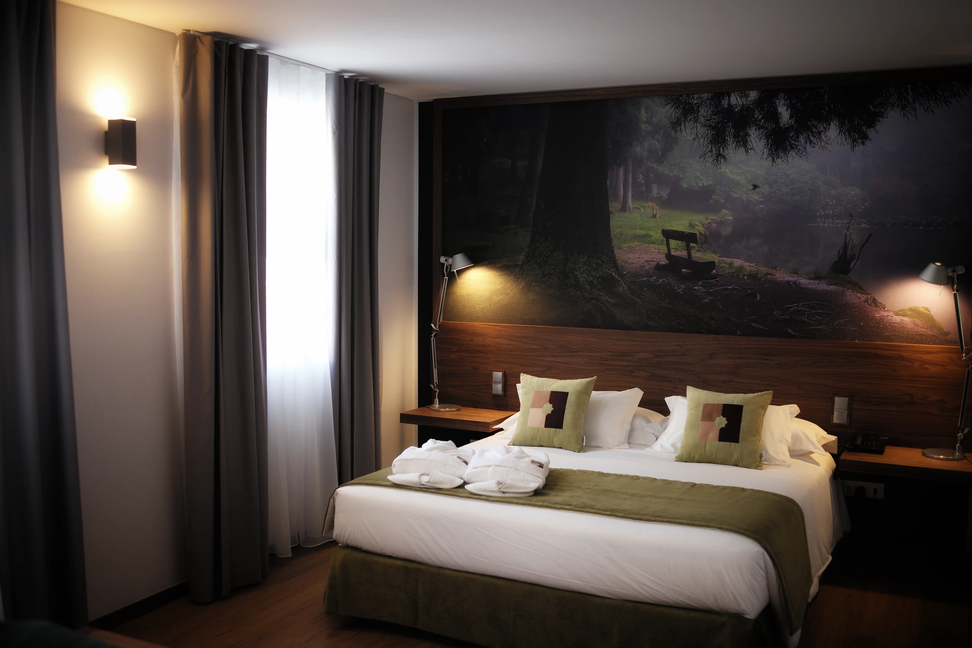 Quarto de hotel elegante com cama, decora&ccedil;&atilde;o natural e cortinas cinzas.