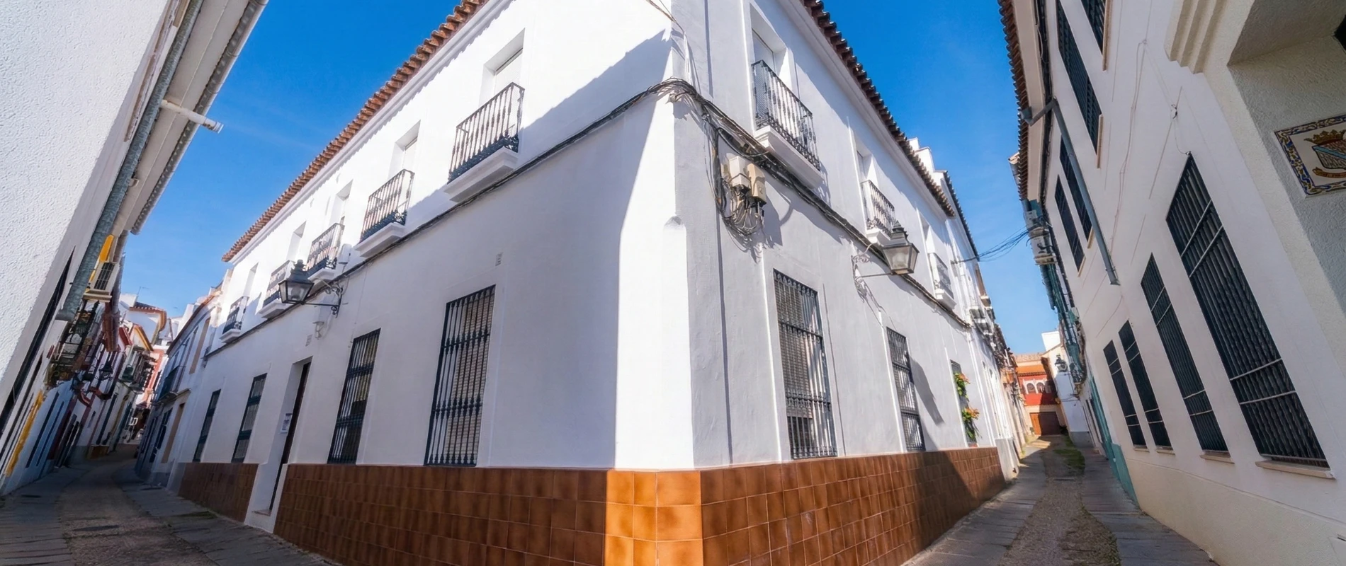 Calle estrecha con edificios blancos y cielo azul brillante.