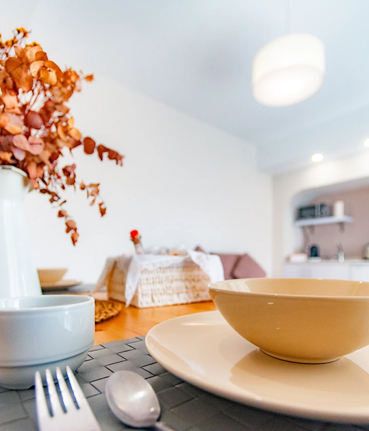 Mesa con vajilla y flores secas en un comedor moderno y luminoso.