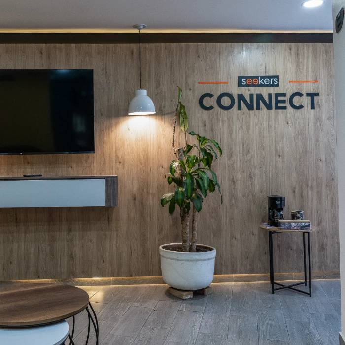 Sala de espera moderna con planta, TV y cartel que dice "CONNECT".