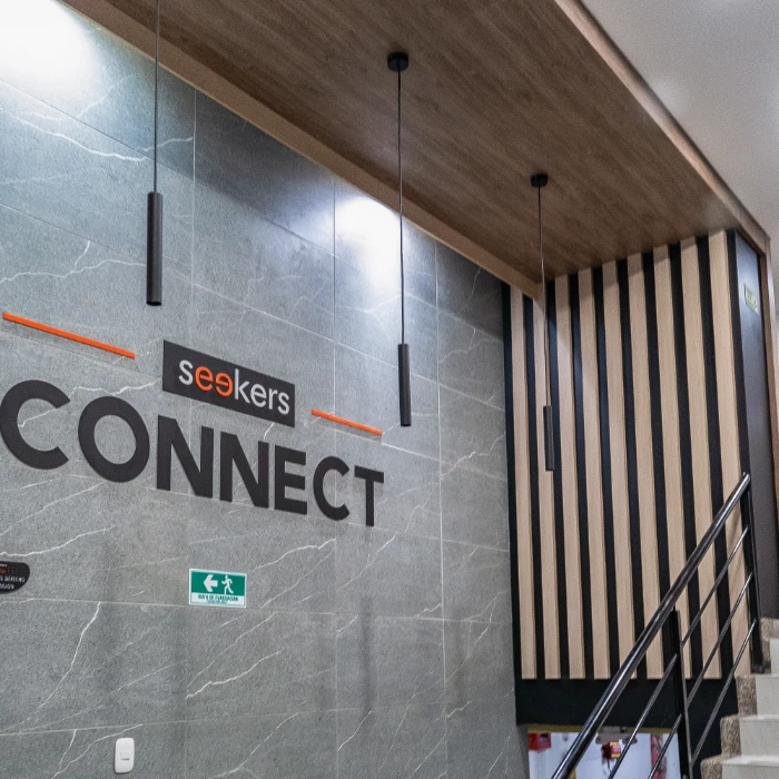 Pared interior con letrero "seekers CONNECT", luces colgantes y escaleras.