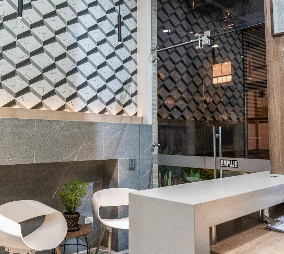 Espacio moderno con sillas blancas y decoraci&oacute;n geom&eacute;trica en pared.