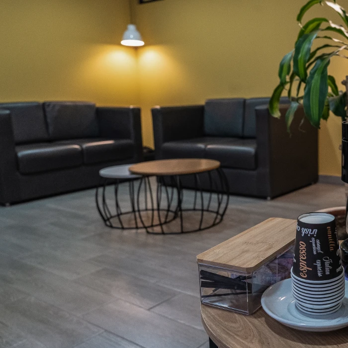 Sala de espera moderna con sillones oscuros y mesa de centro circular.