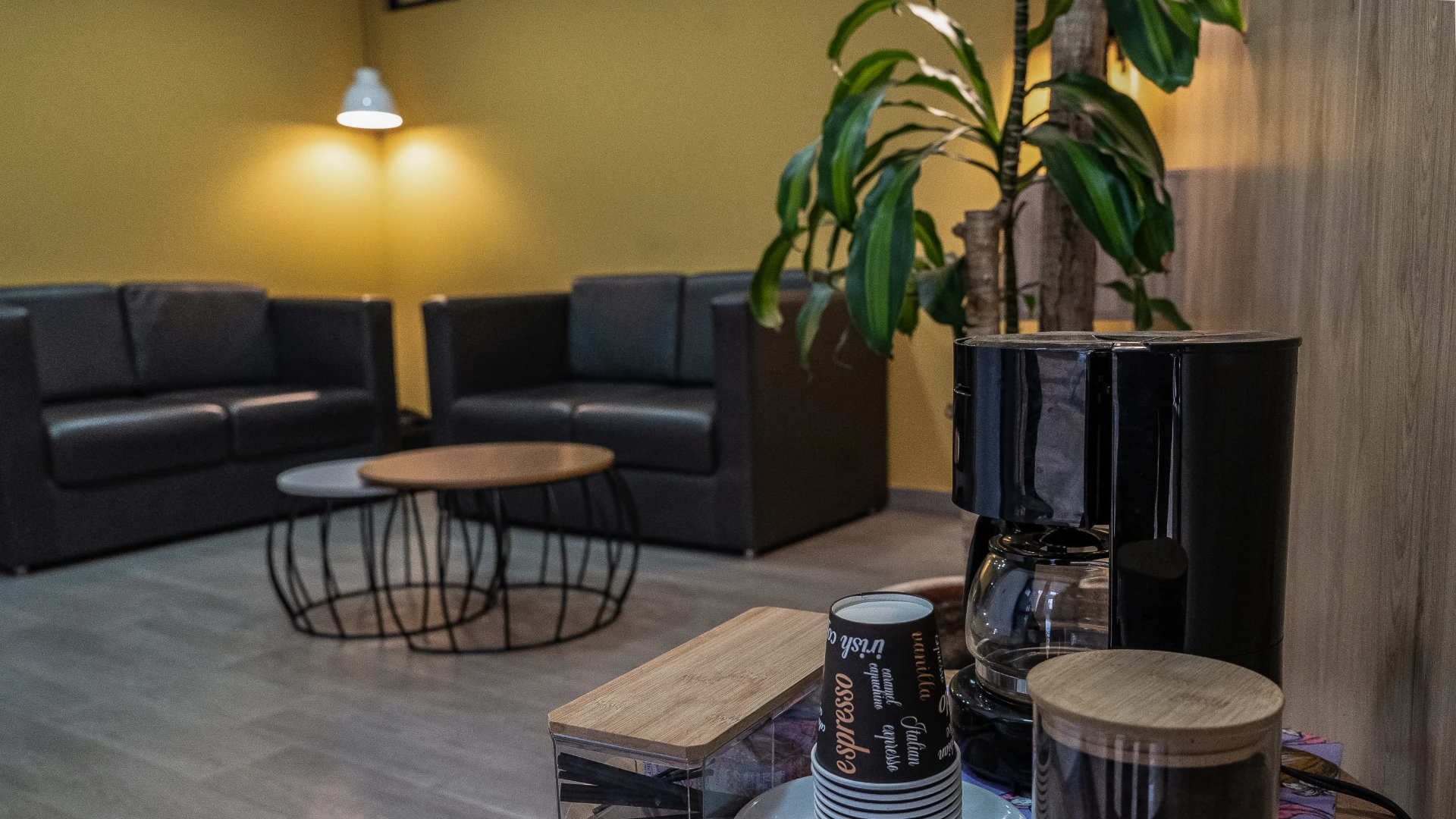 Sala de estar con sof&aacute;s, mesa de caf&eacute; y cafetera en primer plano.