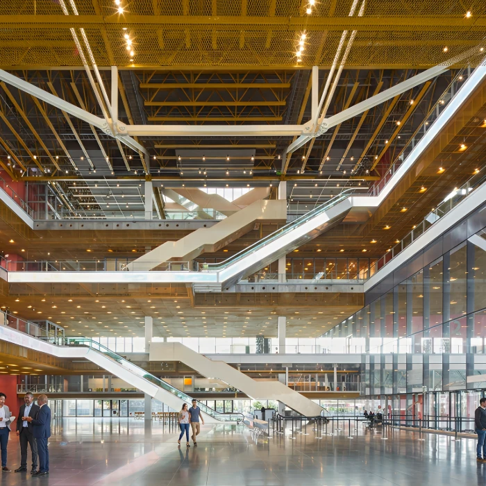Interior moderno con escaleras, gente y reflejos de luces en el techo.