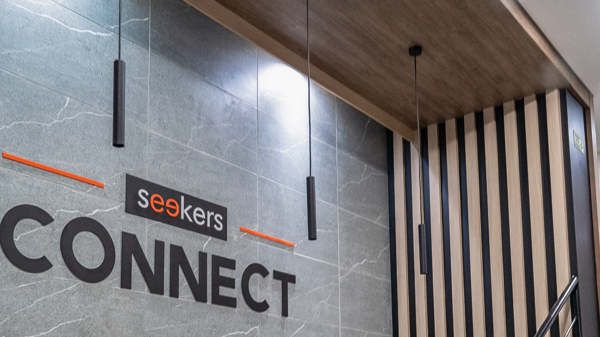 Letrero en una pared que dice "seekers CONNECT" con luces colgantes y paneles.