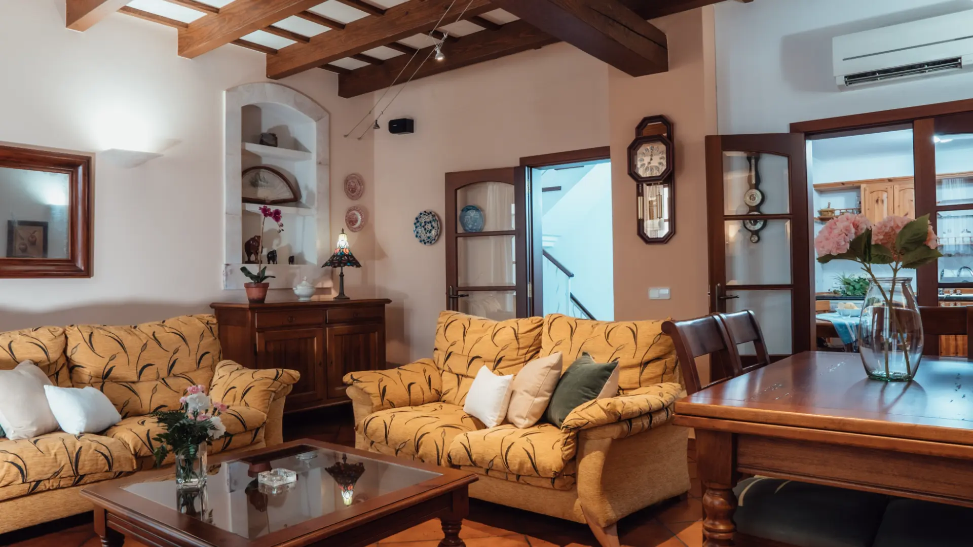 Sala de estar con sof&aacute;s amarillos, mesa de madera y decoraci&oacute;n r&uacute;stica.