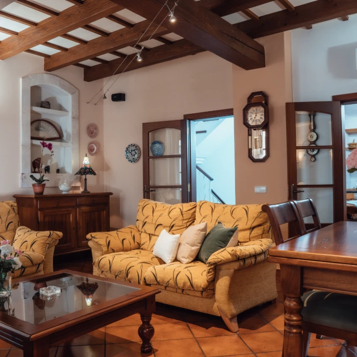 Sala de estar con sof&aacute;s amarillos, mesa de madera y decoraci&oacute;n cl&aacute;sica.