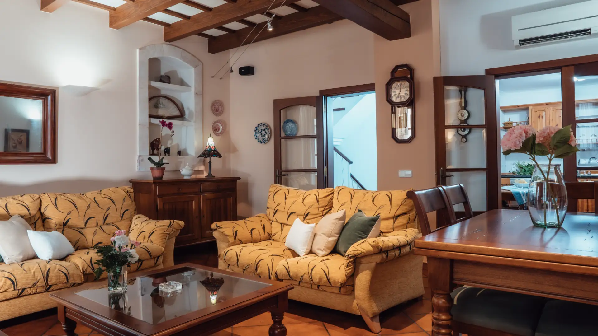 Sala acogedora con sof&aacute;s amarillos, mesa de madera y decoraci&oacute;n cl&aacute;sica.