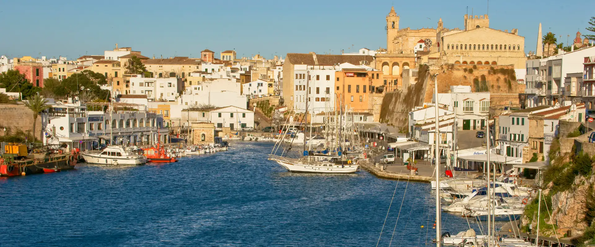 Puerto con barcos y edificios hist&oacute;ricos bajo un cielo despejado.