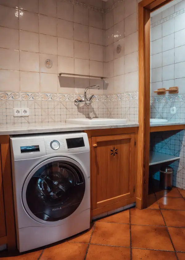 Lavadora en una esquina de lavander&iacute;a con azulejos claros.